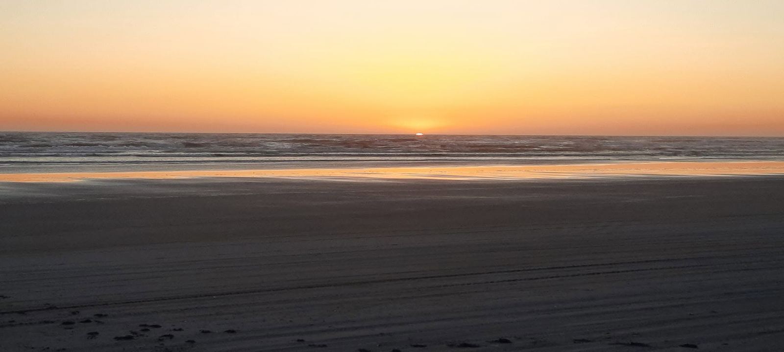 The sun setting over the ocean from an empty beach